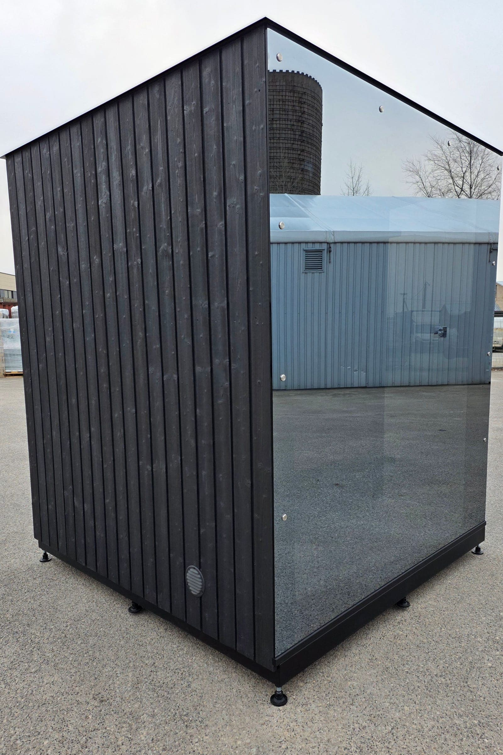Wood Architects cube sauna with black wood cladding and a panoramic glass front